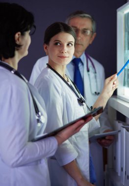 Bir grup doktor bir klinikte röntgenleri inceliyor, teşhis koymayı düşünüyorlar.