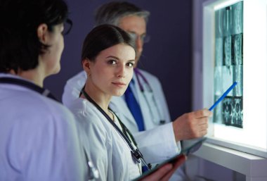 Bir grup doktor bir klinikte röntgenleri inceliyor, teşhis koymayı düşünüyorlar.