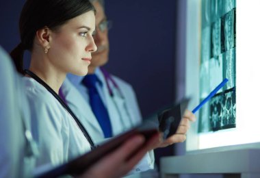 Bir grup doktor bir klinikte röntgenleri inceliyor, teşhis koymayı düşünüyorlar.