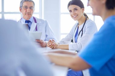 Parlak bir hastane odasında ciddi bir tıbbi ekip bir hastanın hastalığını analiz ediyor.