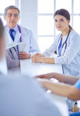 Parlak bir hastane odasında ciddi bir tıbbi ekip bir hastanın hastalığını analiz ediyor.