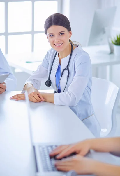 Médecin souriant utilisant un ordinateur portable travaillant avec ses collègues dans une chambre d'hôpital lumineuse — Photo