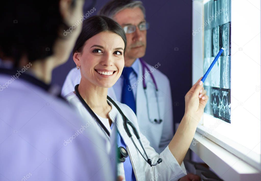 Group of doctors examining x-rays in a clinic, thinking of a diagnosis