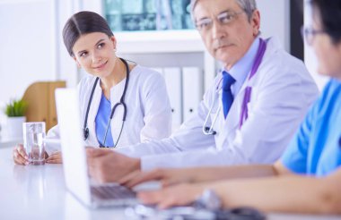 Parlak bir hastane odasında meslektaşlarıyla çalışan gülümseyen bir doktor.