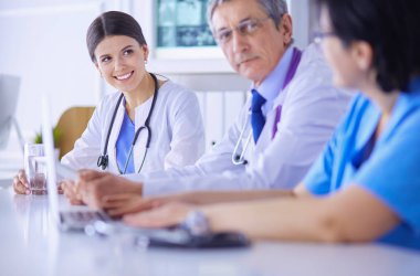 Parlak bir hastane odasında meslektaşlarıyla çalışan gülümseyen bir doktor.