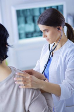 A female doctor listening a patient with a stethoscope clipart