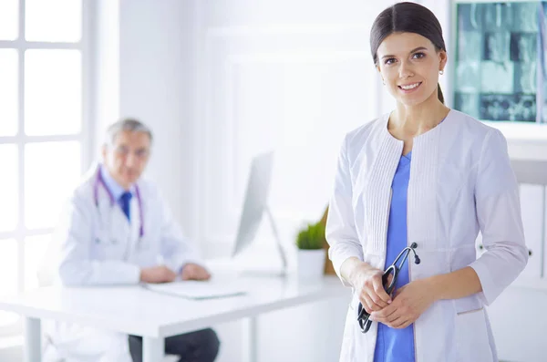 Doktorka se dívá do kamery se svým mužským kolegou v zadní části konferenční místnosti v nemocnici — Stock fotografie