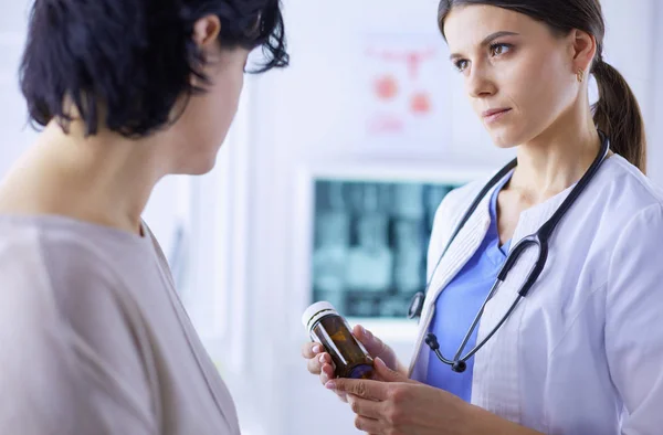 Vacker kvinnlig läkare som förklarar medicinsk behandling för en patient, hålla en flaska läkemedel — Stockfoto