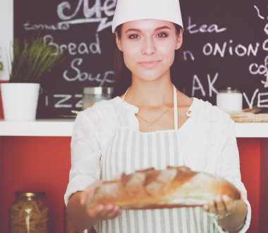 Genç bir kadın mutfağında ekmeği holding ayakta. Genç bir kadın
