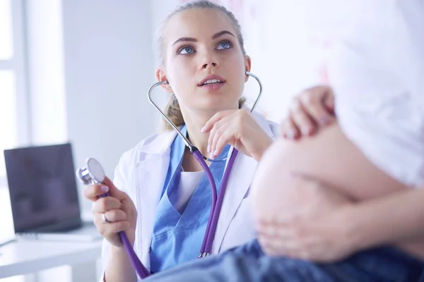 Doctora joven examinando a una mujer embarazada en la clínica. — Foto de Stock