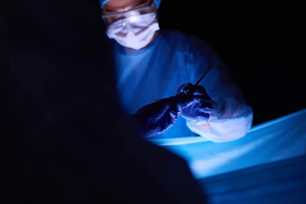 Artsen team in de chirurgie in een donkere achtergrond. — Stockfoto