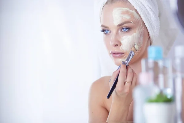 Una foto de una mujer joven aplicando polvo facial en el baño — Foto de Stock