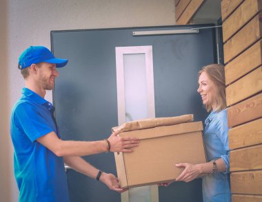 Mavi üniformalı gülümseyen kurye servis konseptine paket kutusu teslim eden teslimatçı. Mavi üniformalı gülümseyen teslimatçı.