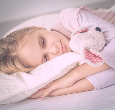 çocuk oyuncak oyuncak ayı ile yatakta uyur küçük kız