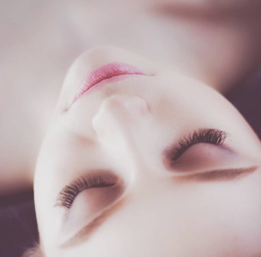 Masaj masasında uzanmış gözleri kapalı rahatlayan genç bir kadın. - Kadın. Spa salonu