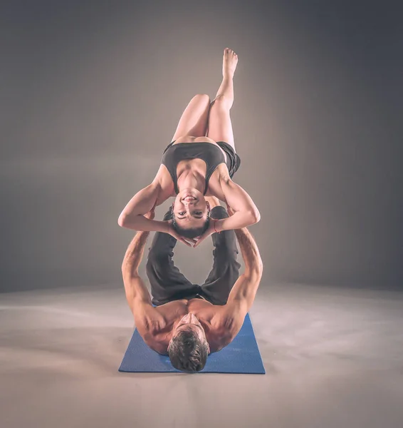 Cuplu tânăr care practică acro yoga pe mat în studio împreună. Acroyoga. Câteva yoga. Partener yoga . — Fotografie, imagine de stoc