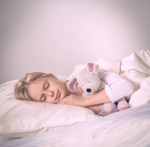 Child little girl sleeps in the bed with a toy teddy bear — Stock Photo, Image