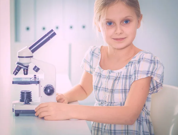 Schoolmeisje op zoek via Microscoop in de wetenschap klasse. — Stockfoto