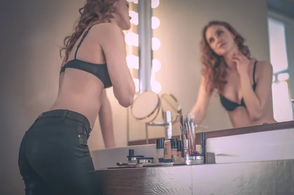 Ung kvinna tittar sig i spegeln på badrum. — Stockfoto