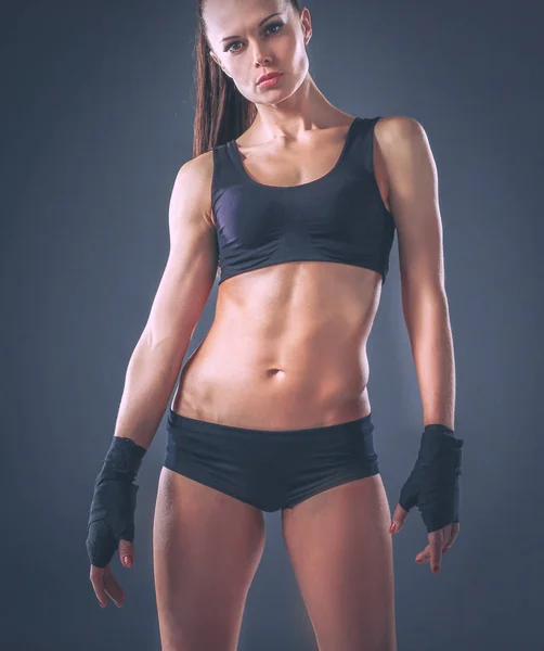 Muskulös ung kvinna stående på grå bakgrund — Stockfoto