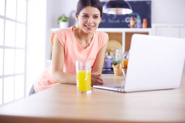 Mutfakta dizüstü bilgisayara benzeyen tariflerle gülümseyen genç bir kadın. Gıda blogcusu kavramı