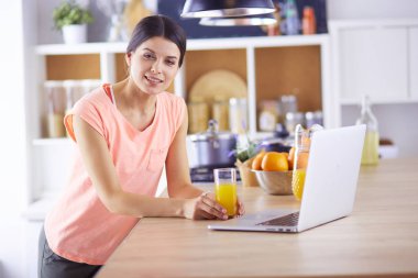 Mutfakta dizüstü bilgisayara benzeyen tariflerle gülümseyen genç bir kadın. Gıda blogcusu kavramı