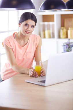 Mutfakta dizüstü bilgisayara benzeyen tariflerle gülümseyen genç bir kadın. Gıda blogcusu kavramı