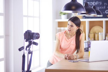 Mutfakta dizüstü bilgisayara benzeyen tariflerle gülümseyen genç bir kadın. Gıda blogcusu kavramı