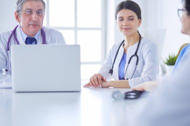 Parlak bir ofiste çalışan ciddi bir tıbbi ekip.