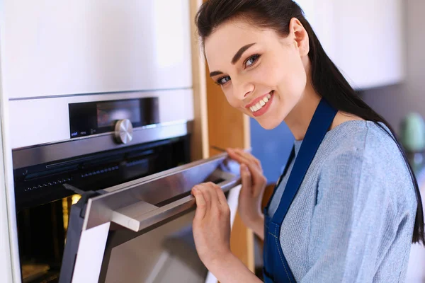 Hermosa joven comprobando cómo le va a su pastel en el horno — Foto de Stock