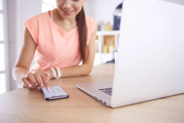 Vacker kvinna på telefon med bärbar dator hemma i köket — Stockfoto