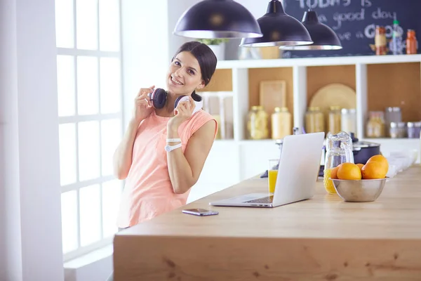 Hezká žena na telefonu pomocí notebooku doma v kuchyni — Stock fotografie