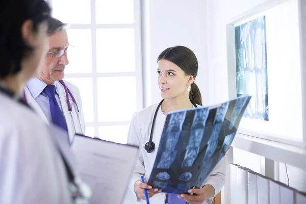Usmívající se lékaři diskutující o diagnóze pacientů při pohledu na rentgeny v nemocnici — Stock fotografie