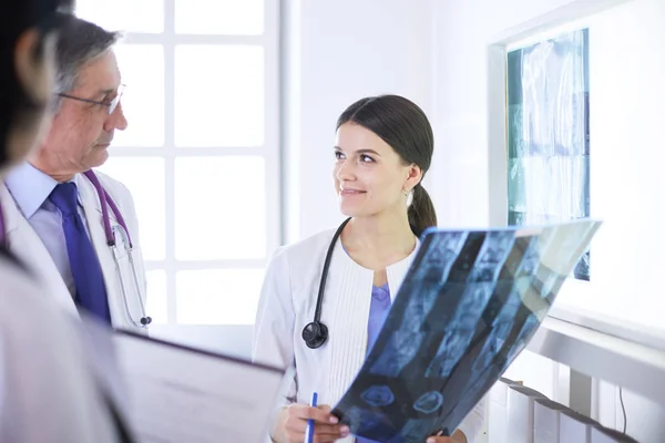 Mosolygó orvosok beszélgetnek a betegek diagnózisáról, miközben röntgenfelvételeket nézegetnek a kórházban. — Stock Fotó