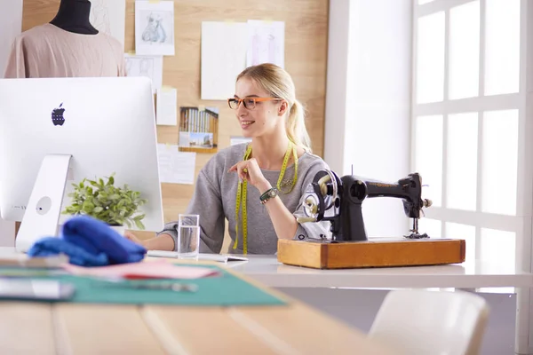 Jonge vrouw met behulp van laptop mode ontwerper werken in de achtergrond in de studio — Stockfoto