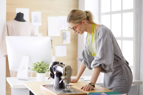 Creare nuovi stili alla moda. Allegro giovane donna cucire mentre seduto al suo posto di lavoro nel laboratorio di moda — Foto Stock