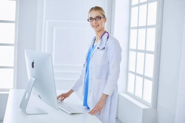 Young doctor woman standing near table, isolated on white background — Stock Photo, Image