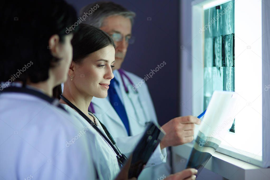 Group of doctors examining x-rays in a clinic, thinking of a diagnosis