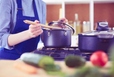 Mutfakta ahşap kaşıkla yemek pişiren kadın