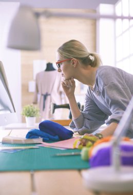 dizüstü bilgisayar ve elbise formu ile stüdyoda çalışan moda tasarımcısı