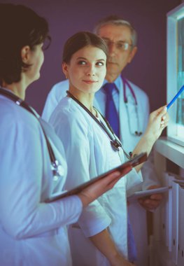 Bir grup doktor bir klinikte röntgenleri inceliyor, teşhis koymayı düşünüyorlar.
