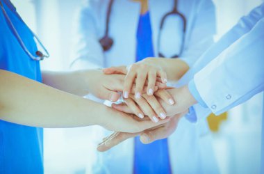Bir grup doktor ellerini birleştiriyor. Yakın plan.