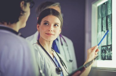 Bir grup doktor bir klinikte röntgenleri inceliyor, teşhis koymayı düşünüyorlar.