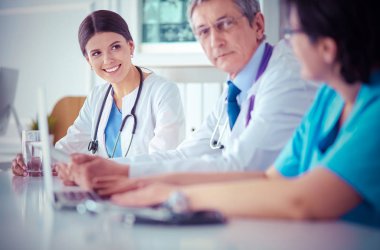 Parlak bir hastane odasında meslektaşlarıyla çalışan gülümseyen bir doktor.