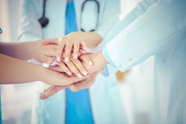 Bir grup doktor ellerini birleştiriyor. Yakın plan.