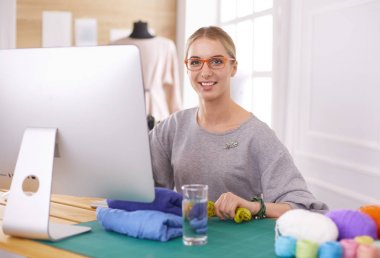 Moda tasarımcıları stüdyoda çalışıyor. Masanın üzerinde oturuyorlar.