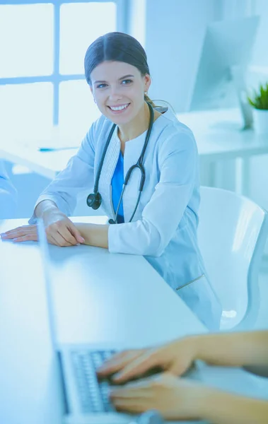 Smiling doctor using a laptop working with her colleagues in a bright hospital room — Stock Photo, Image