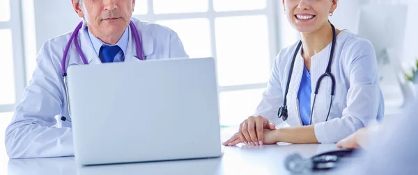 Equipo médico serio utilizando un ordenador portátil en una sala de consulta luminosa —  Fotos de Stock