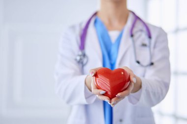 Kalbi tutan steteskoplu bir doktor, beyaz arka planda izole edilmiş.