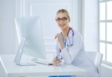 Hastanede masasında oturan genç bir kadın doktorun portresi.